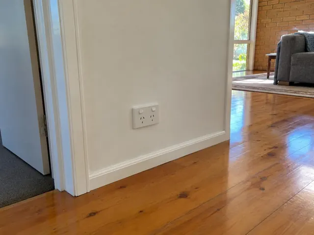 Double power point on a white wall beside a doorway in a polished timber-floored home in Carrara
